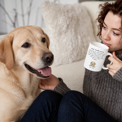 Persona con una taza con el texto "Liebe Hundemama" y un labrador retriever en un sofá claro.