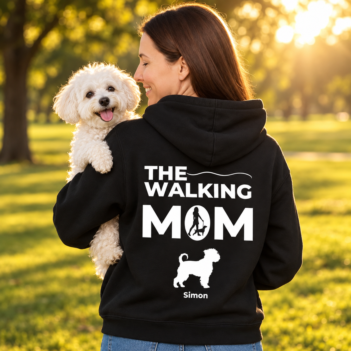 Sudadera con capucha negra con el texto "The Walking Mom", personalizada con foto de perro y nombre. La lleva una mujer al aire libre.