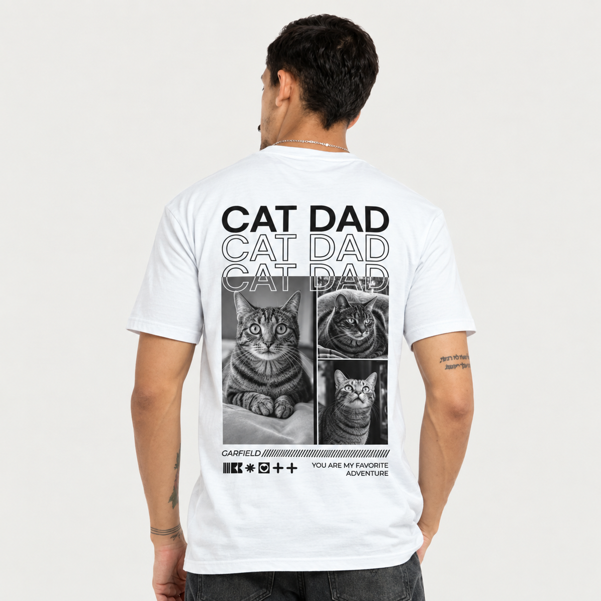Camiseta blanca con impresión negra, en la espalda fotos de gatos y el texto "CAT DAD".
