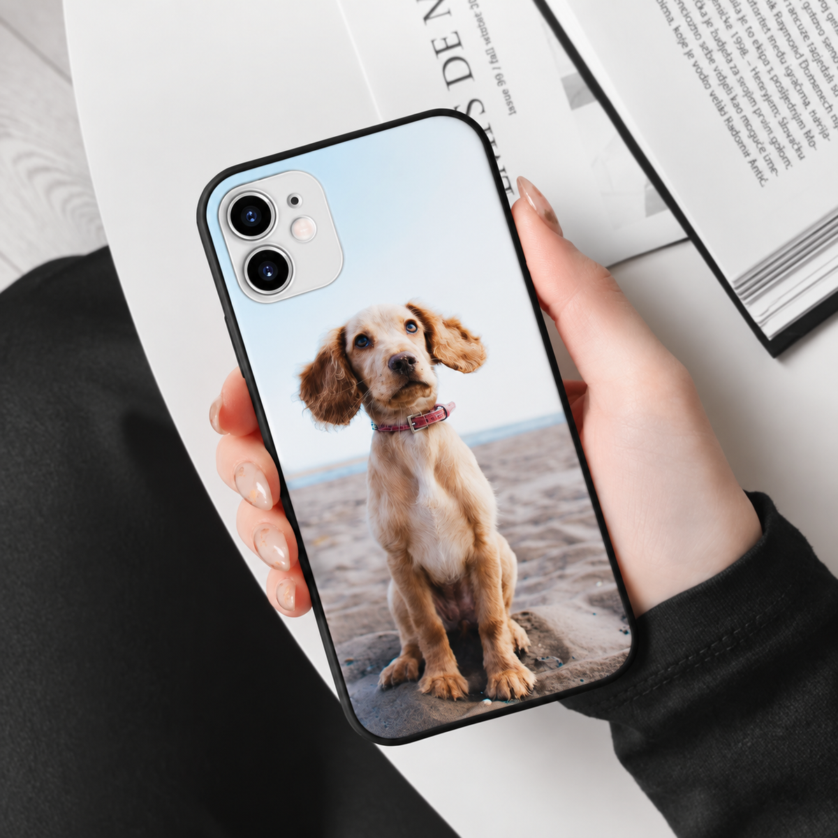 Funda de móvil negra personalizada con foto de un perro, sostenida por una persona.
