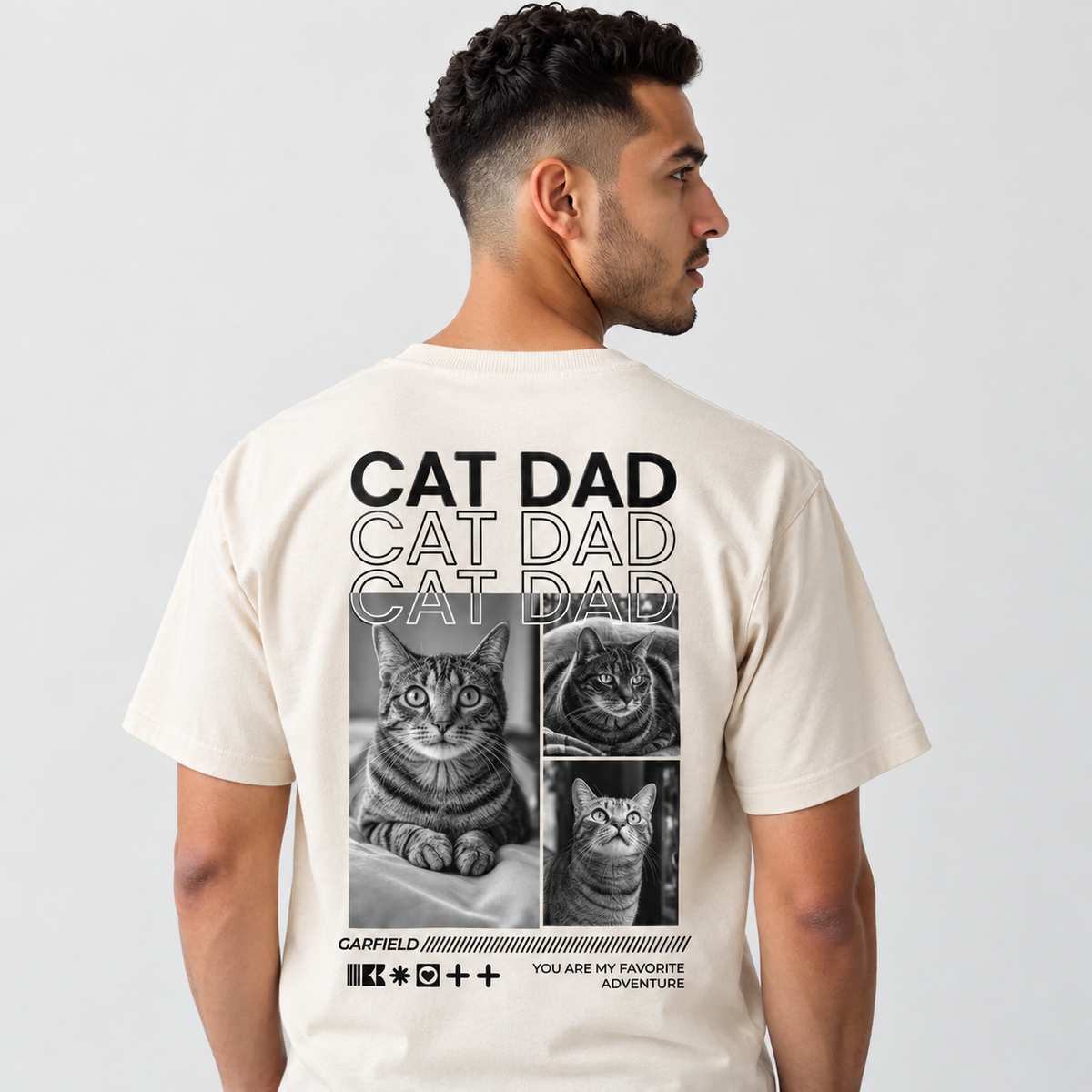 Camiseta beige con motivo de gato y el texto "CAT DAD" en la espalda.
