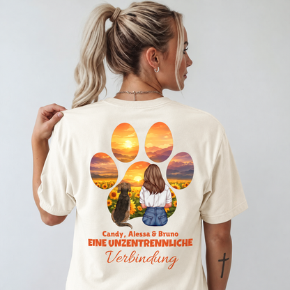 Camiseta beige con impresión en color de una mujer y un perro ante un paisaje de girasoles.