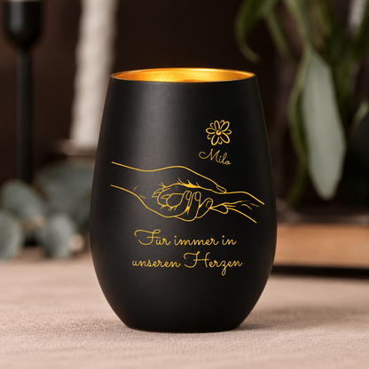 Luz conmemorativa negra con interior dorado, personalizada con diseño de manos y el texto "Für immer in unseren Herzen".