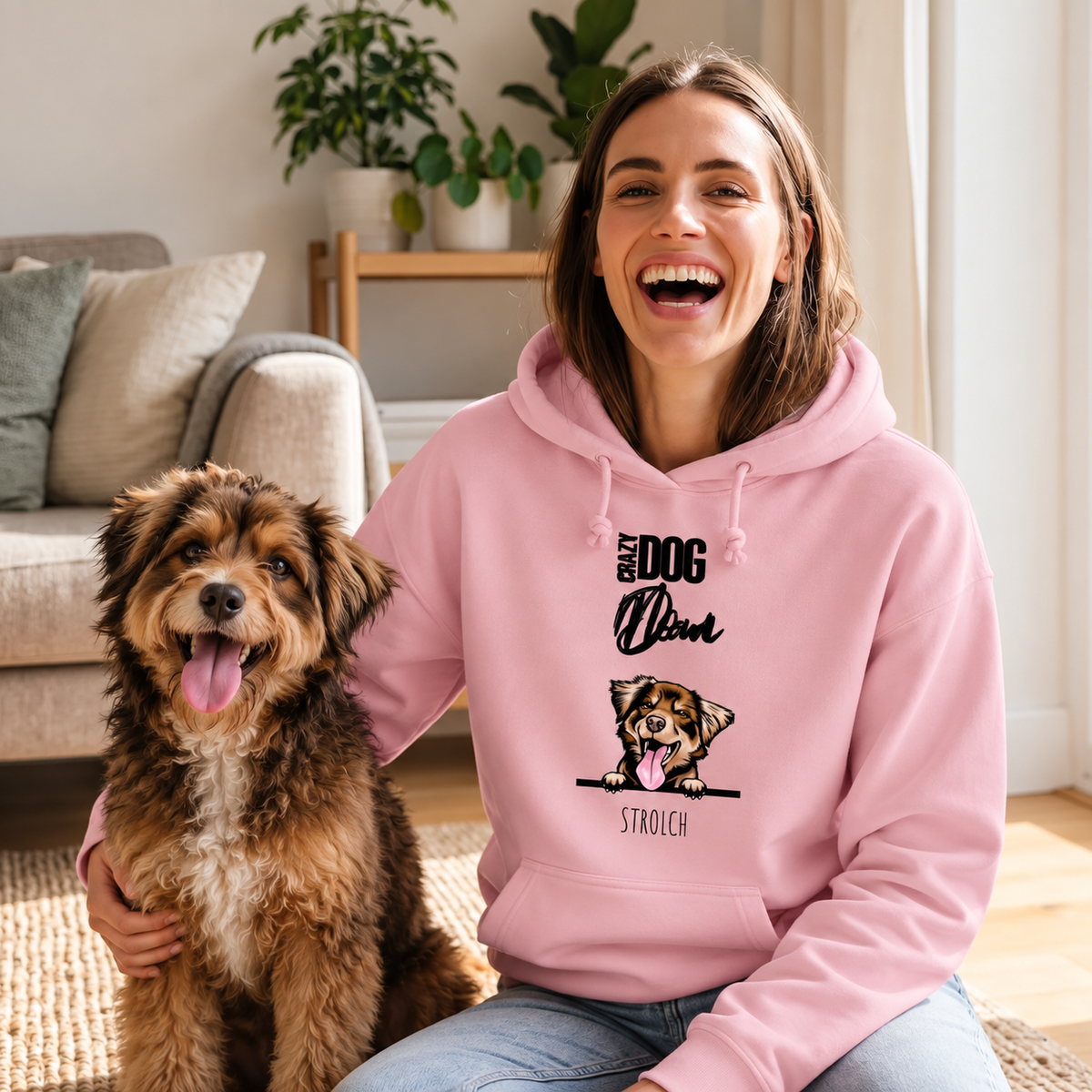 Mujer sonriente con sudadera rosa con motivo de perro, sentada junto a un perro en una alfombra.