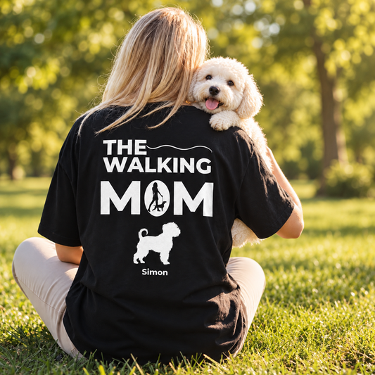 Camiseta negra personalizada con el texto "THE WALKING MOM" y motivo de perro. Sentada al aire libre.