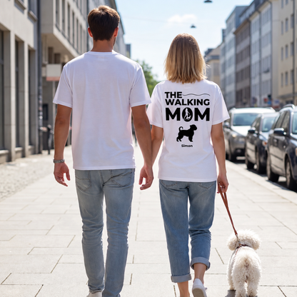 Dos personas con camisetas blancas con el texto "THE WALKING MOM" y un perro, en la calle.