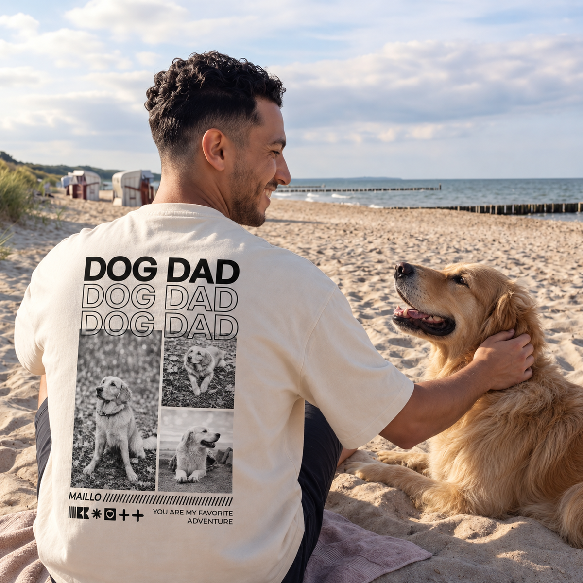 Camiseta beige con el texto "DOG DAD", llevada por un hombre en la playa con un golden retriever.