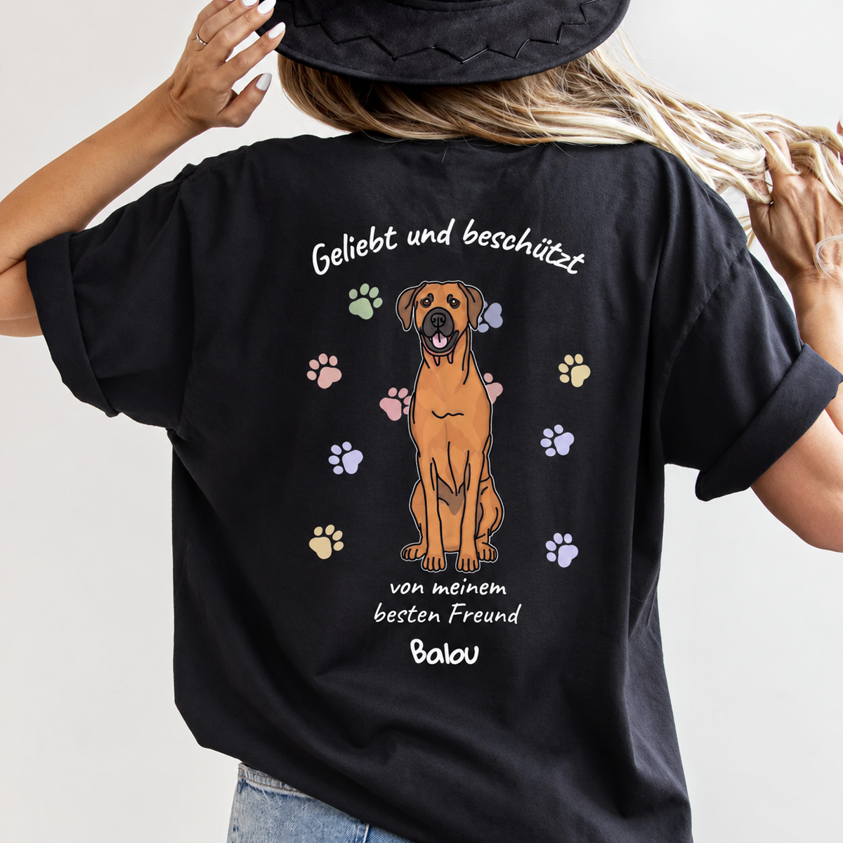 Camiseta negra con ilustración de perro y el texto "Geliebt und beschützt" en la espalda.