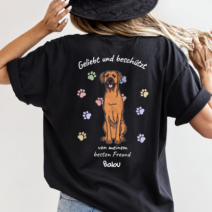Camiseta negra con ilustración de perro y el texto "Geliebt und beschützt" en la espalda.