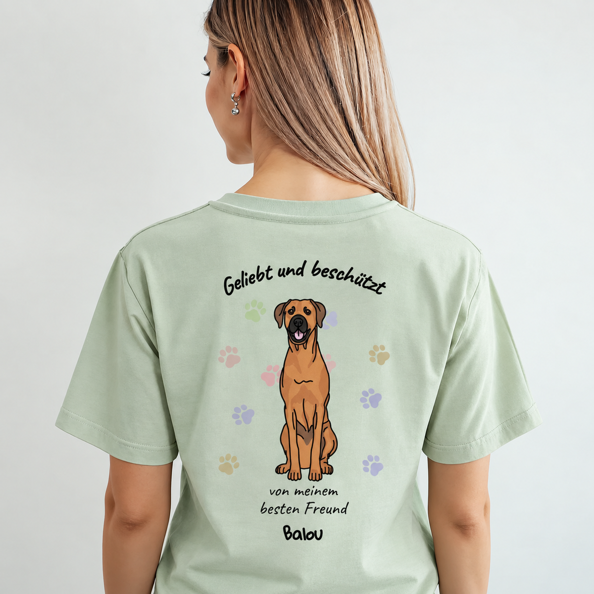 Camiseta verde claro con estampado de perro y el texto "Geliebt und beschützt" en la espalda.