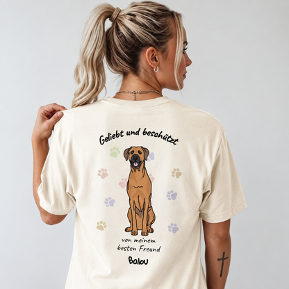 Camiseta beige con diseño de perro y el texto "Geliebt und beschützt" en la espalda.
