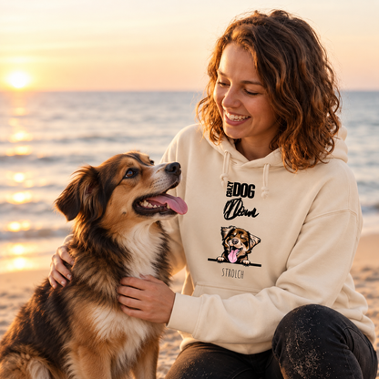 Sudadera con capucha beige con motivo de perro, llevada por una persona en la playa al atardecer.