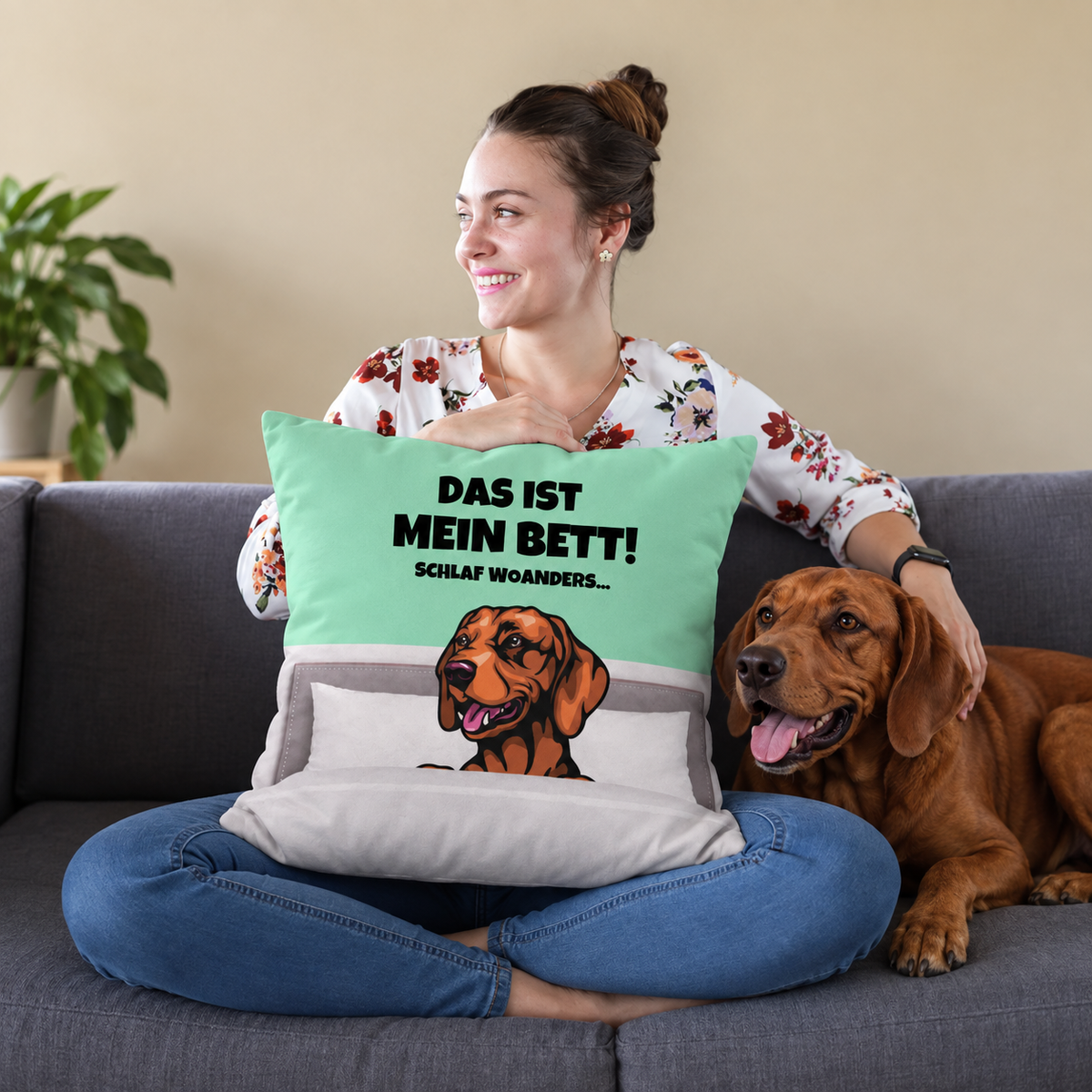 Cojín personalizado con motivo de perro y texto en verde menta y gris, en un sofá con una mujer y un perro.