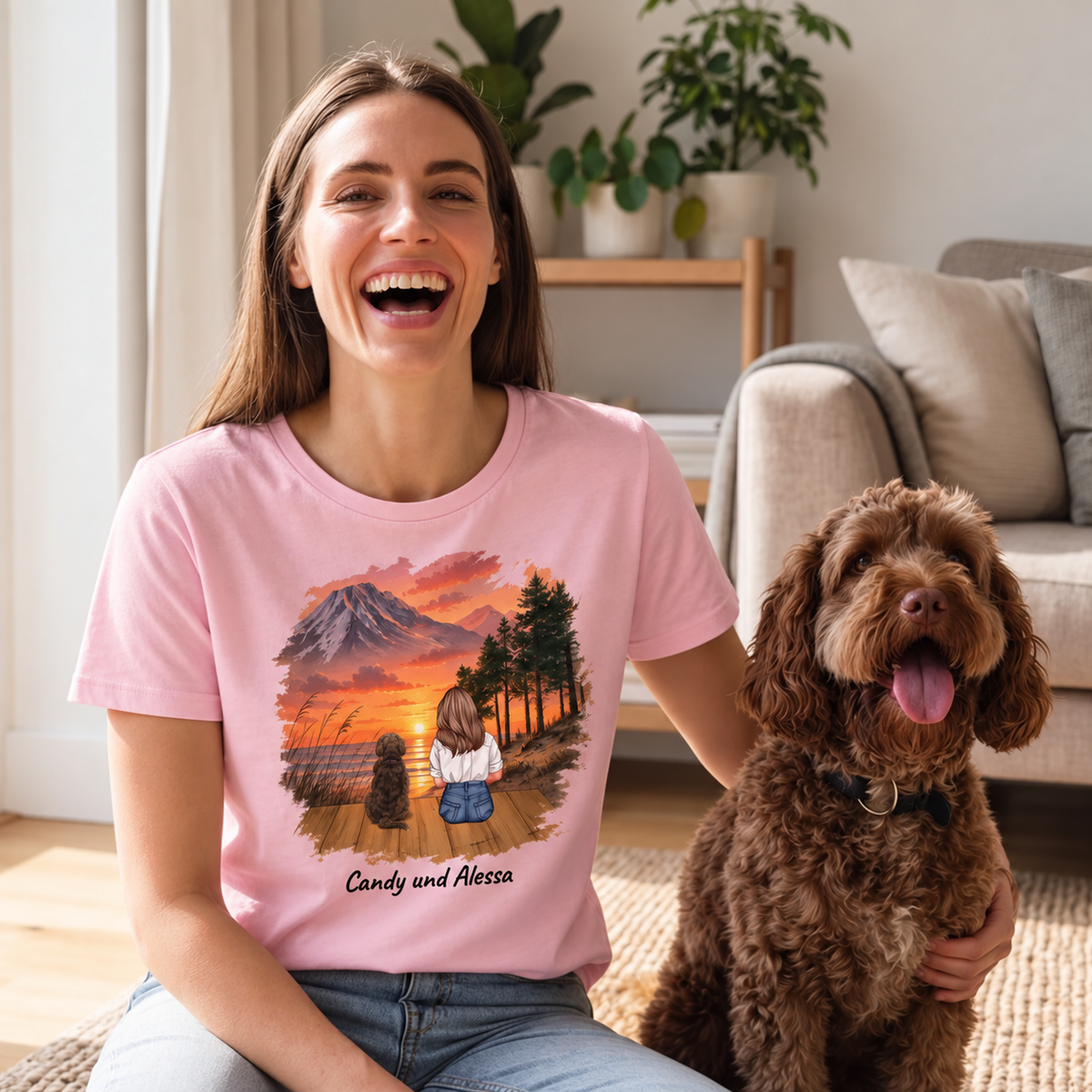 Camiseta rosa con impresión personalizada de una mujer y dos perros ante un paisaje al atardecer.