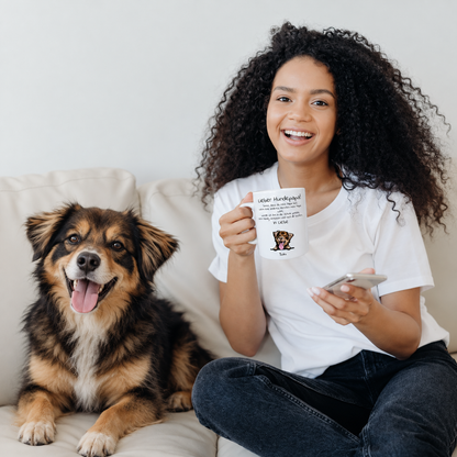 Mujer con taza personalizada "Lieber Hundepapa" sentada junto a un perro en un sofá. La taza muestra foto y texto.
