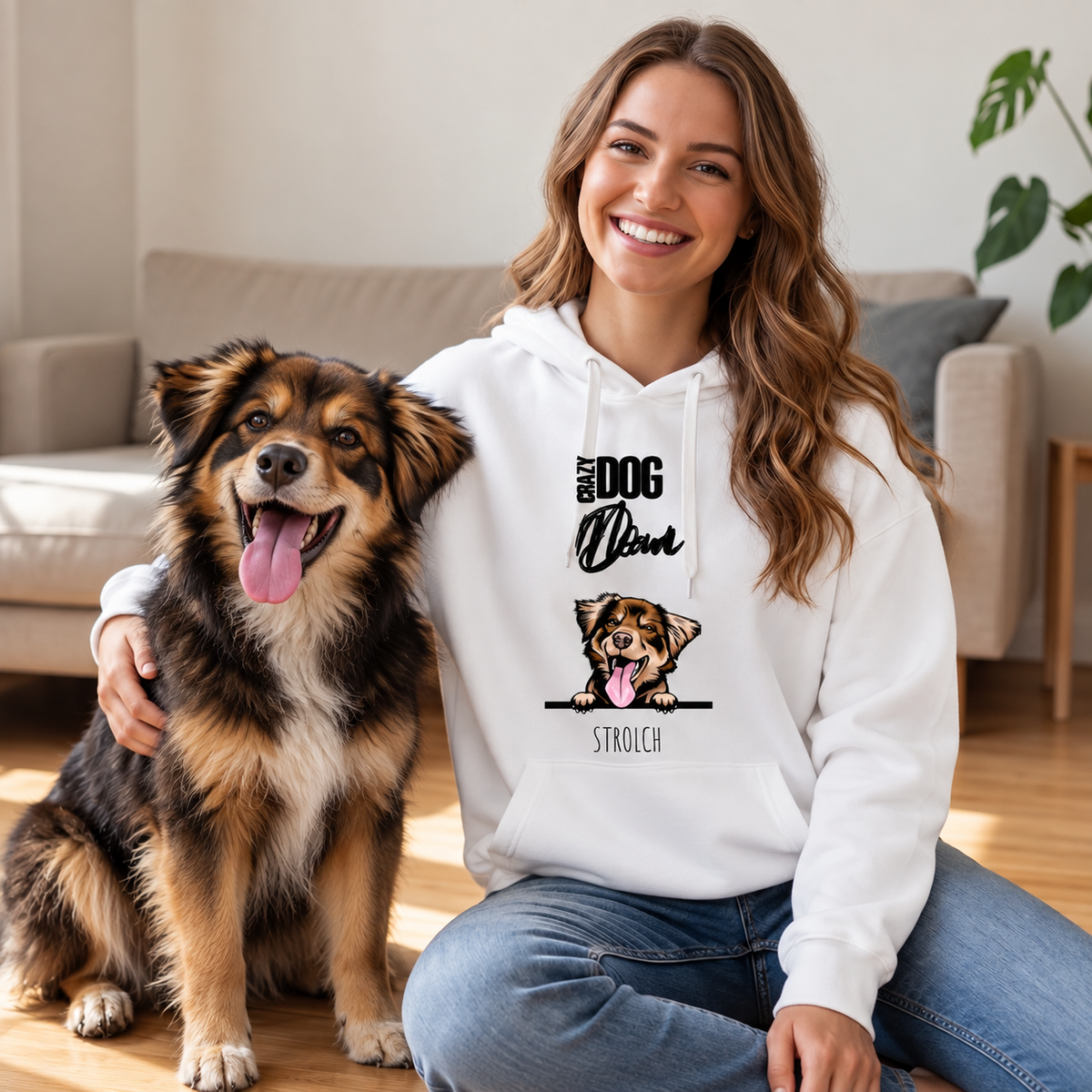 Persona sonriente con sudadera blanca y un perro en un suelo de madera, ambiente hogareño. La sudadera muestra un perro.