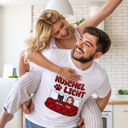 Camiseta blanca con el texto "Kuschel Licht" y figuras de dibujos animados de una pareja y un gato.