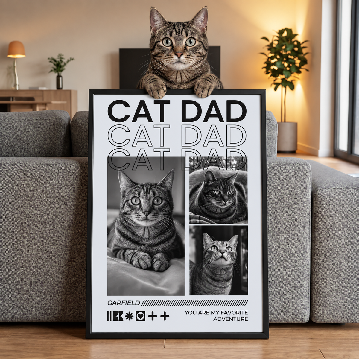 Gato sentado sobre un póster personalizado con el texto "CAT DAD" y fotos de distintos gatos.