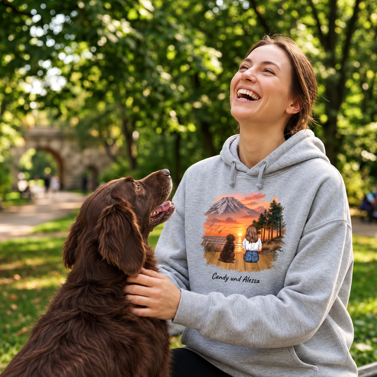 Sudadera con capucha gris con impresión personalizada de un paisaje y dos animales, llevada por una mujer sonriente.