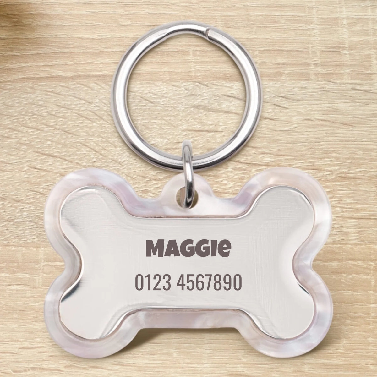 Placa para perro de epoxi personalizada en forma de hueso con el nombre Maggie y un número de teléfono.