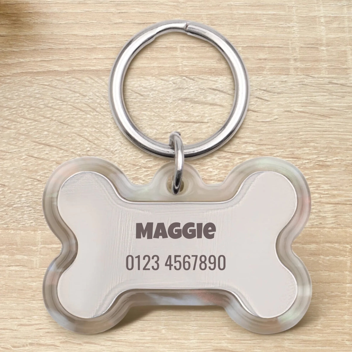 Placa para perro de epoxi personalizada en forma de hueso con el nombre "Maggie" y un número de teléfono.