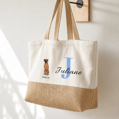 Bolsa de compras beige con asas, personalizada con la inicial “J” y una imagen de perro. Mitad inferior de yute.