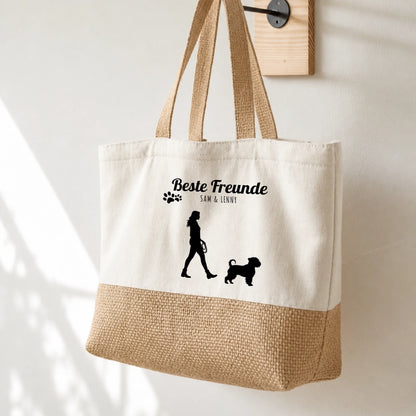Bolsa de compras beige con impresión negra, silueta de persona y perro, personalizada con nombres.