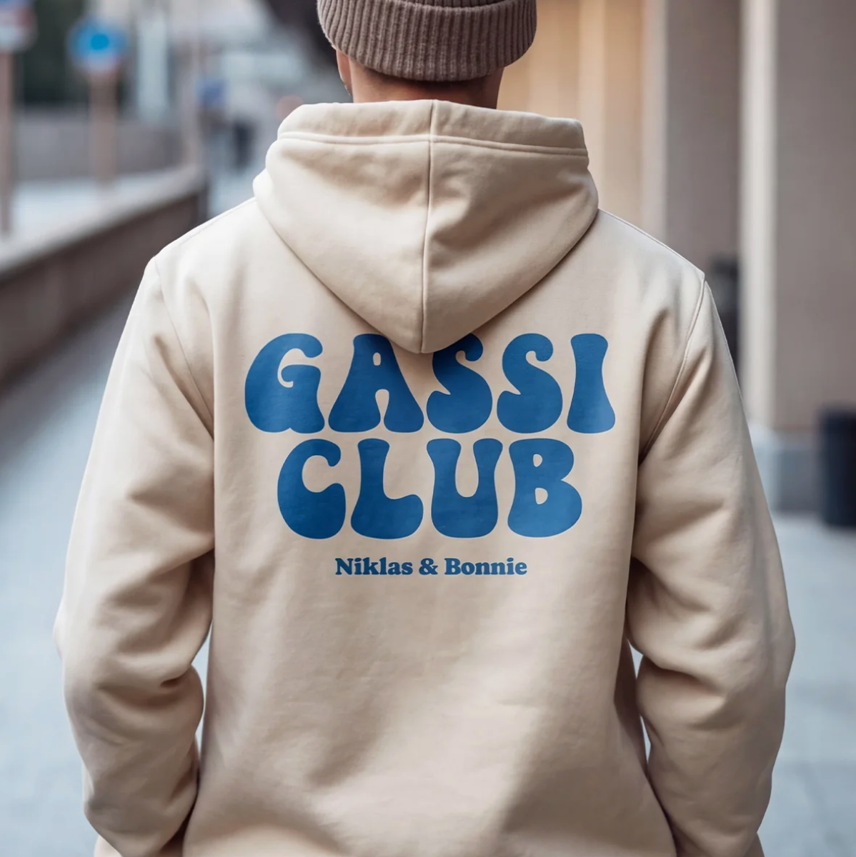 Sudadera con capucha beige con el texto azul "GASSI CLUB" y los nombres "Niklas & Bonnie" en la espalda.