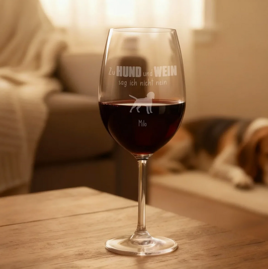 Copa de vino grabada personalizada llena de vino tinto, con motivo de perro y nombre, sobre mesa de madera.