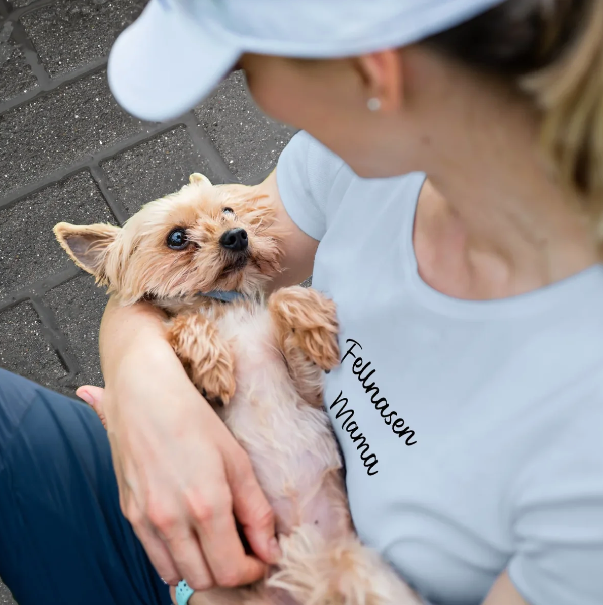 Camiseta azul con el texto "Fellnasen Mama", llevada por una persona que sostiene un perro.