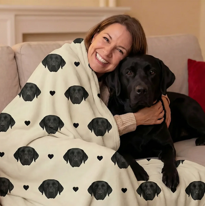 Manta personalizada con cabezas de perros negras sobre fondo beige, envolviendo a una mujer sonriente.