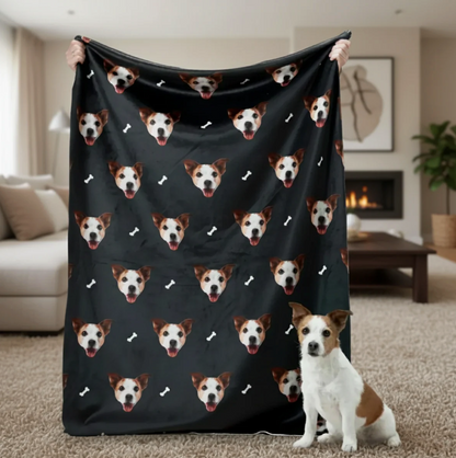 Manta personalizada con cabezas de mascotas sobre fondo negro, sostenida por una persona con un perro en primer plano.