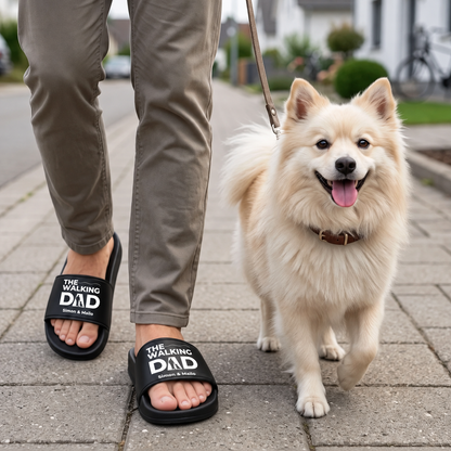Persona con chanclas negras personalizadas con el estampado "THE WALKING DAD" paseando a un perro.